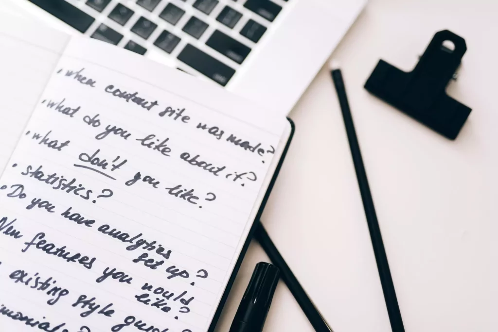 A close-up view of a notebook with handwritten notes alongside a laptop for planning and strategy.