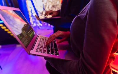 Two professionals analyzing data on laptops with colorful lighting, focusing on cybersecurity details.